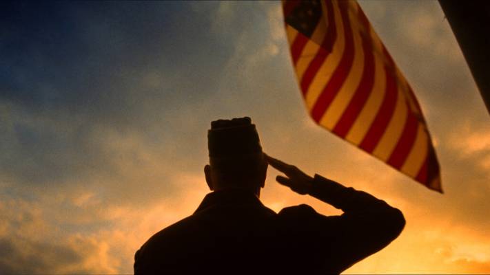 A U.S. veteran salutes the American flag at sunset, honoring our heroes